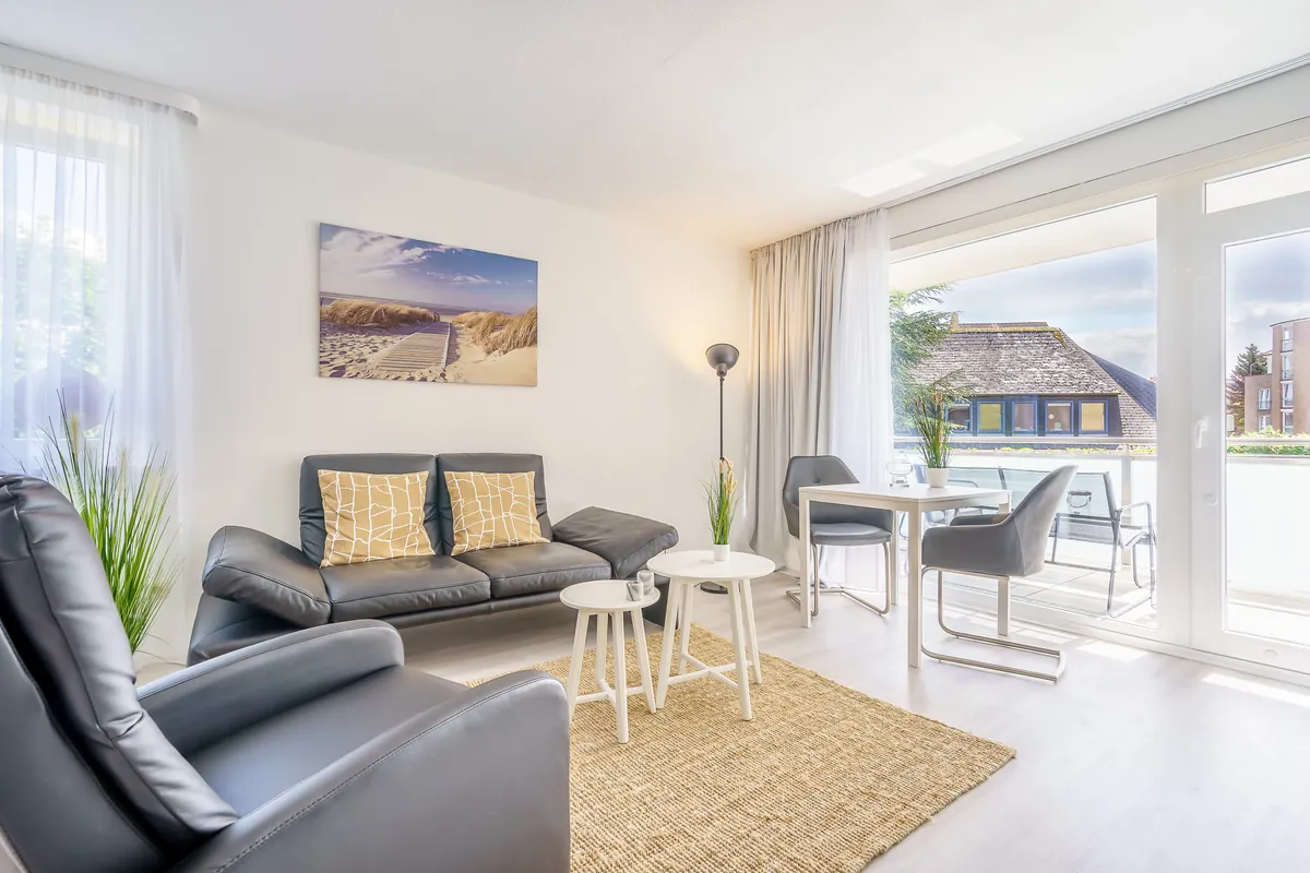 Helles Wohnzimmer der Fewo North East mit Ledersofa und Balkonzugang